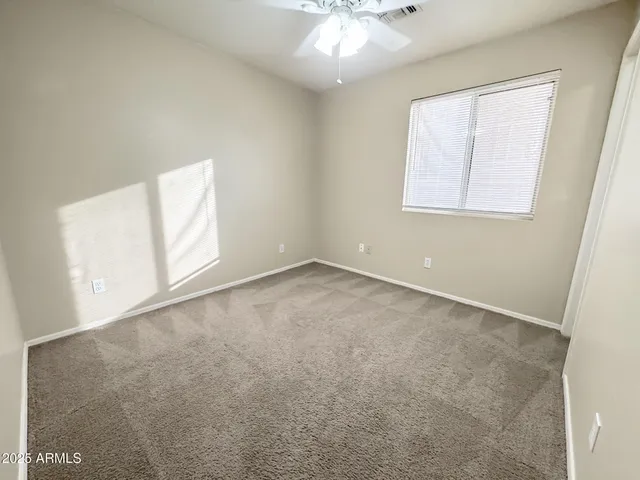 an empty room with windows and chandelier fan