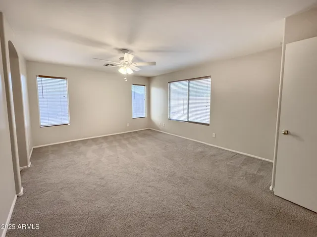 an empty room with windows and ceiling fan