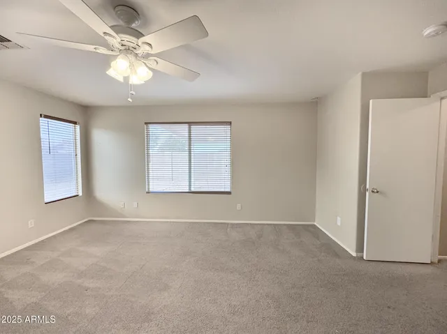 an empty room with windows and fan