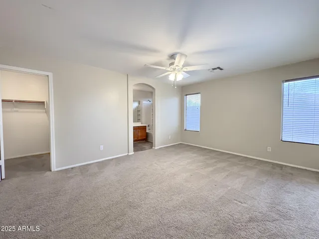 an empty room with windows and fan
