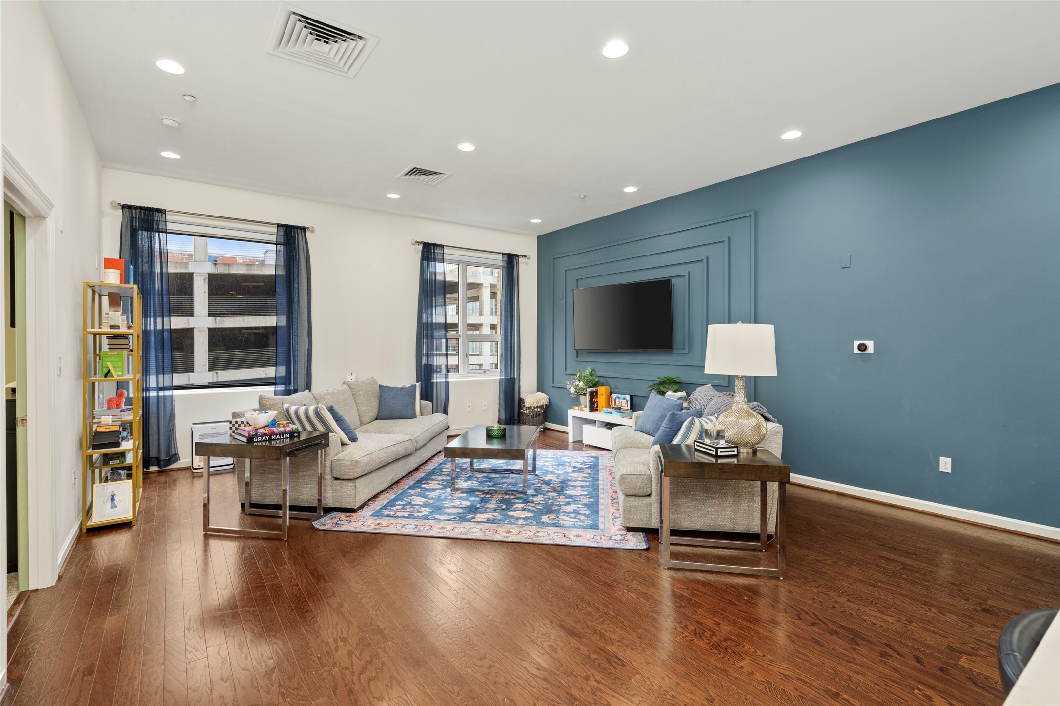 914 Main Street, Unit 1008 Houston, TX 77002 - Photo 7 of 26 Family room accented with a pop of color and abundant natural light from the windows, featuring updated wood flooring.
