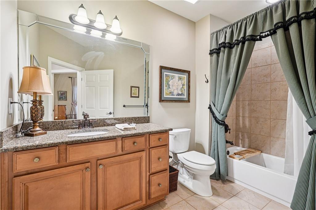 4334 Lanier Ridge Walk, Unit 1403 Cumming, GA 30041 - Photo 22 of 29 a bathroom with a granite countertop sink a toilet a mirror a vanity and shower