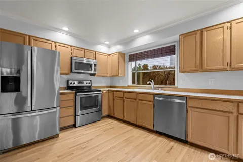 a kitchen with a sink a microwave a refrigerator and cabinets