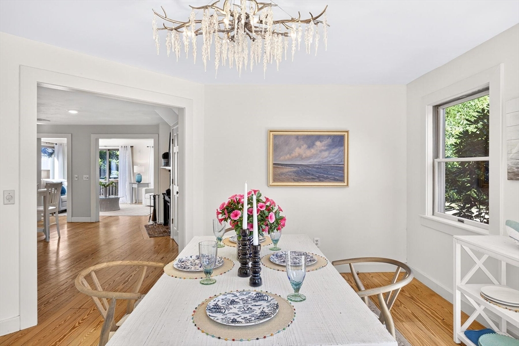 80 Log Cabin Road Eastham, MA 02642 - Photo 16 of 41 a dining room with wooden floor a chandelier a wooden table and chairs