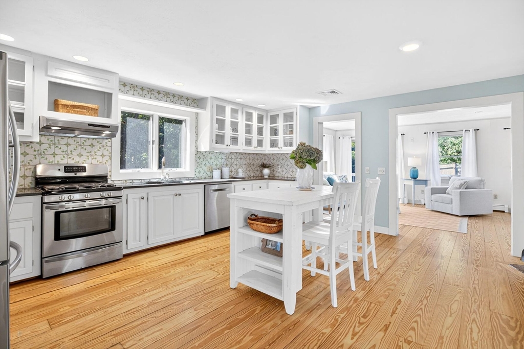 80 Log Cabin Road Eastham, MA 02642 - Photo 6 of 41 a kitchen with stainless steel appliances a stove a sink dishwasher a microwave oven and a dining table with wooden floor