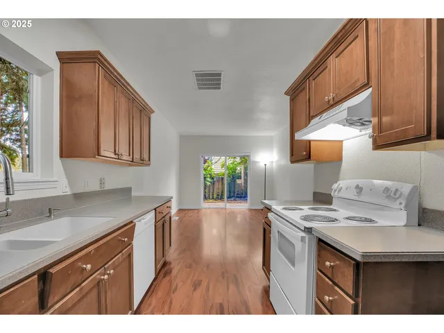 a kitchen that has a sink a stove and wooden cabinets
