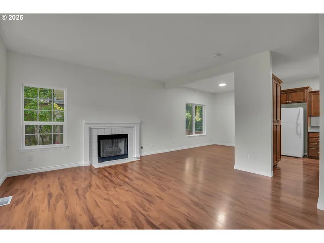 a view of an empty room with window and wooden floor