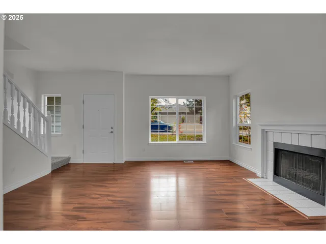 a view of an empty room with a window and wooden floor