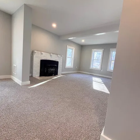 an empty room with windows and fireplace