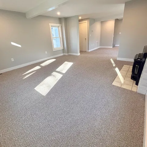 a view of an empty room with window and a kitchen area