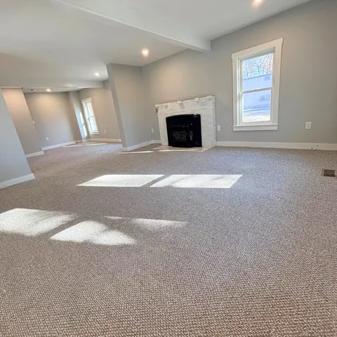a view of an empty room with a window and fireplace