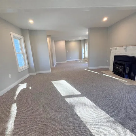 an empty room with windows and fireplace