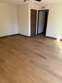 a view of an empty room with wooden floor and closet