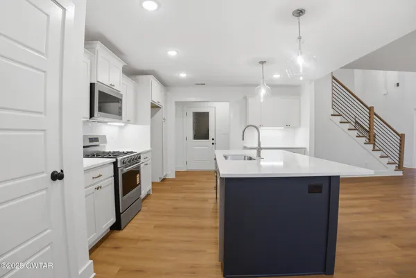 a kitchen with kitchen island a sink wooden floor and white cabinets