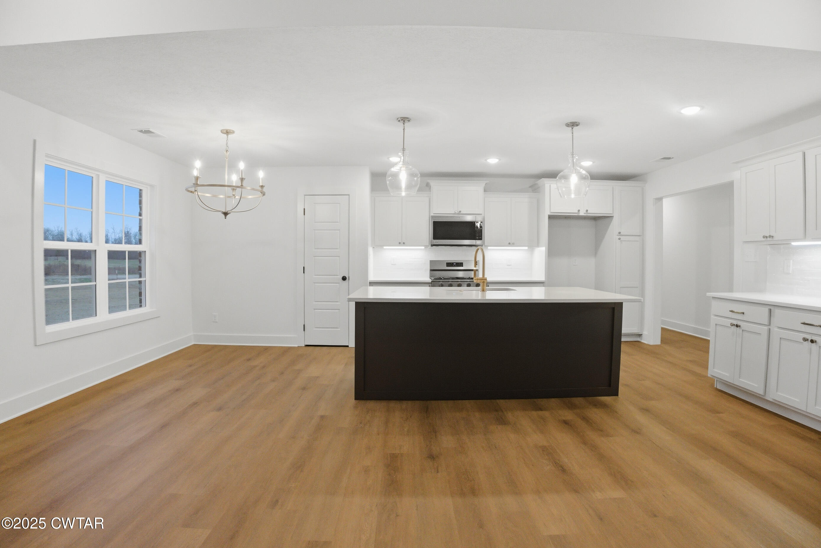 164 Daybreak Loop Medina, TN 38355 - Photo 12 of 40 a kitchen with kitchen island a sink wooden floor and white cabinets