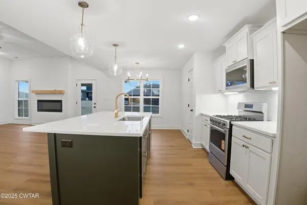 a view of an empty room with wooden floor and a ceiling fan
