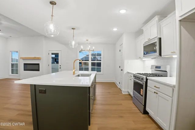 a view of an empty room with wooden floor and a ceiling fan