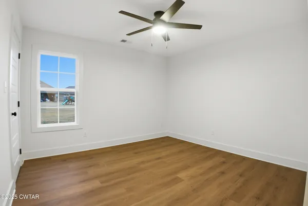 an empty room with a window and a fan