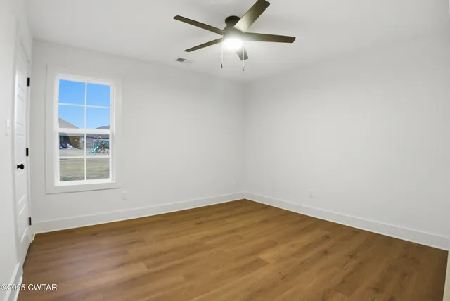 an empty room with a window and a fan