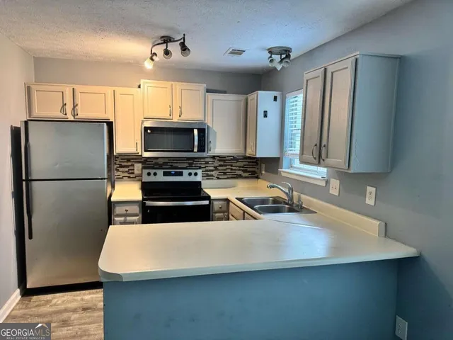 a kitchen with stainless steel appliances a refrigerator a stove a sink a center island and a cabinets