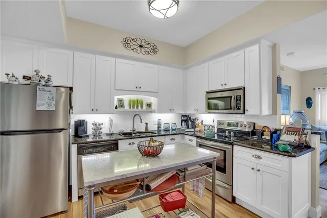 a kitchen with stainless steel appliances a stove a sink a microwave a refrigerator and cabinets