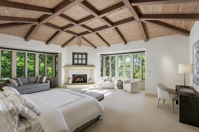a bedroom with furniture large window and a fireplace