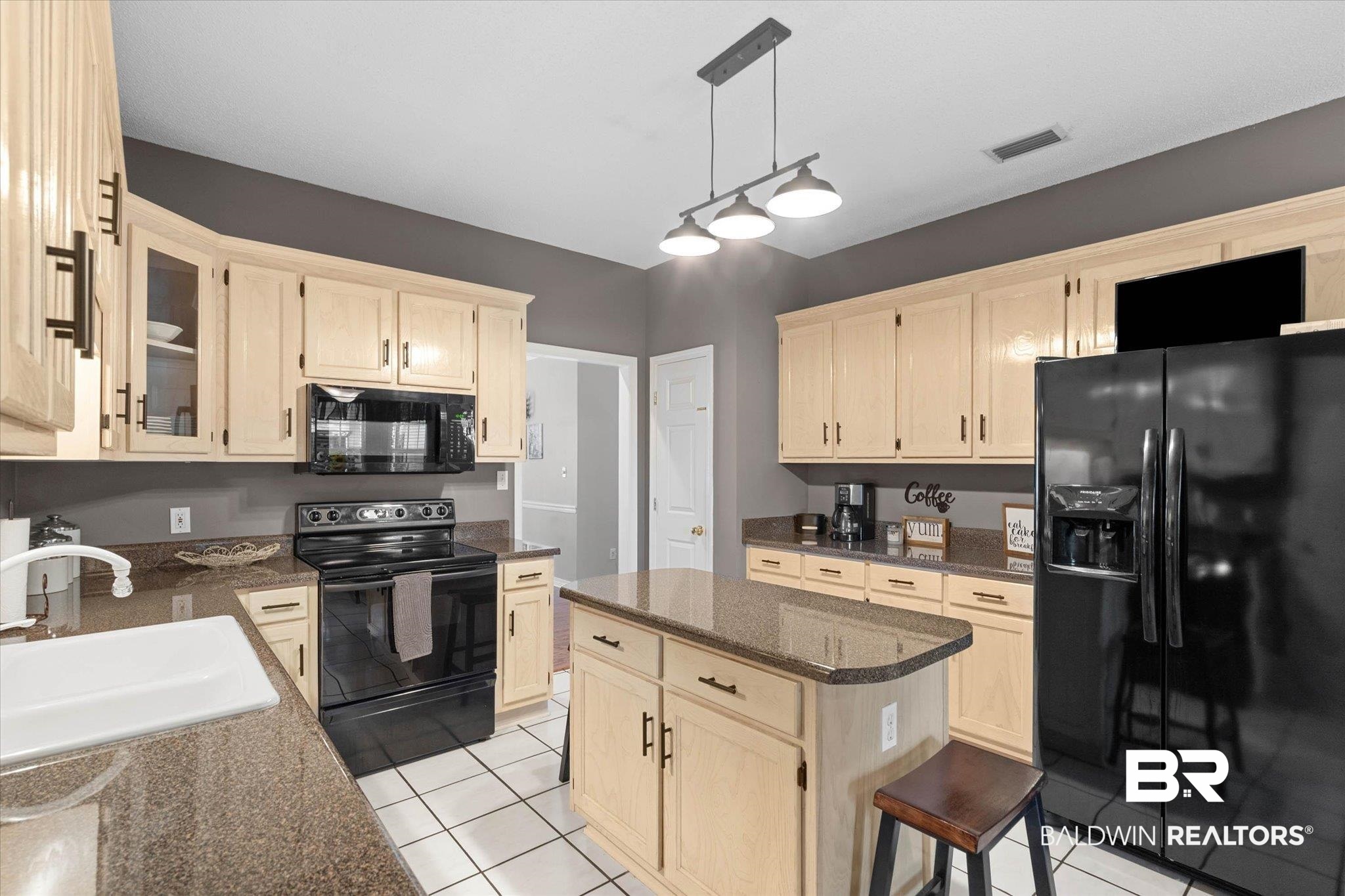 3170 Scott Dairy Loop Road West Mobile, AL 36695 - Photo 8 of 24 Kitchen featuring light wood-finish cabinetry, dark countertops, black appliances, a central island, and white tile flooring