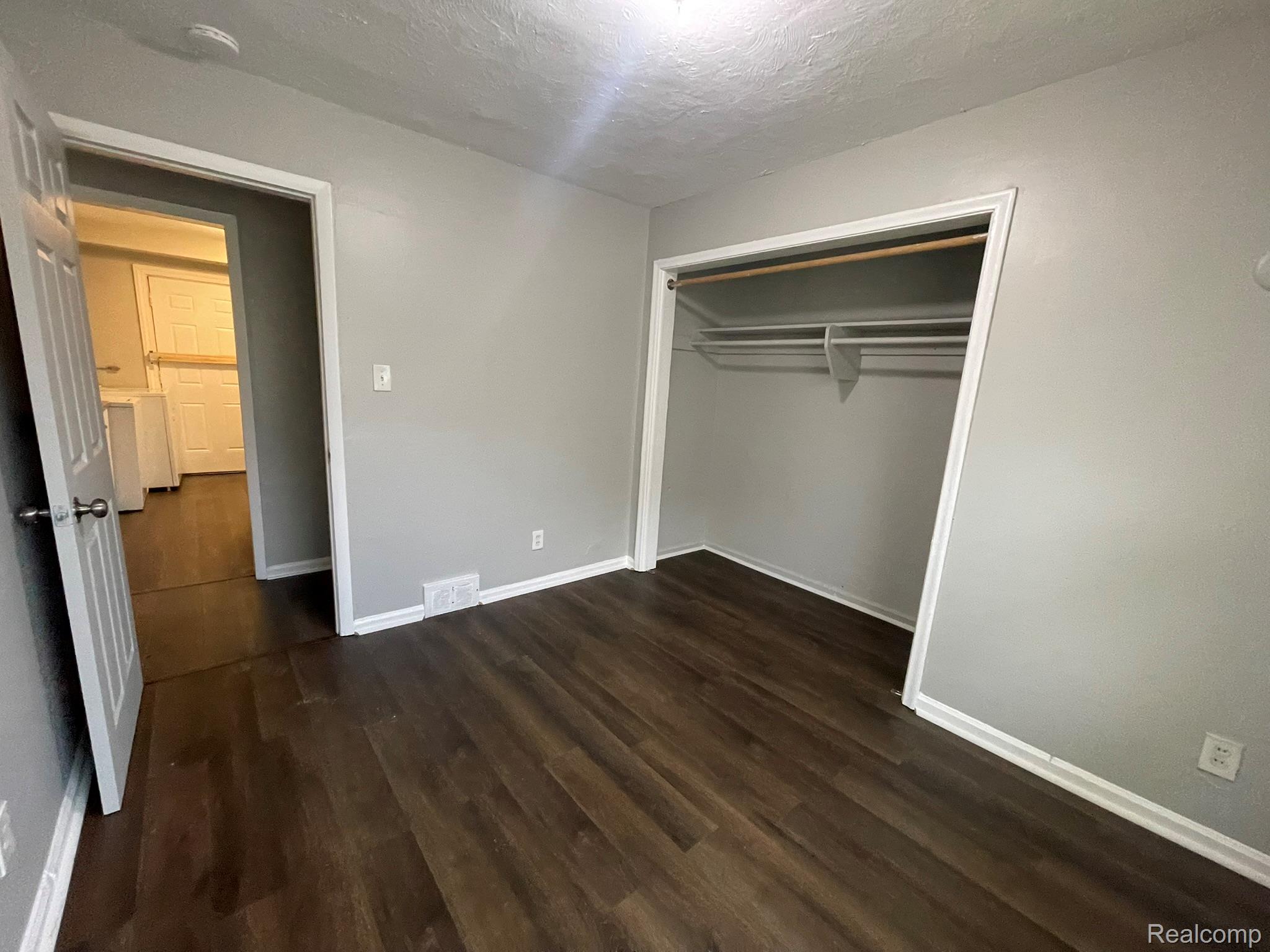 19800 Berg Road Detroit, MI 48219 - Photo 9 of 13 Room featuring wood-finish flooring, light grey walls, white trim, and an open closet with shelving and hanging rods