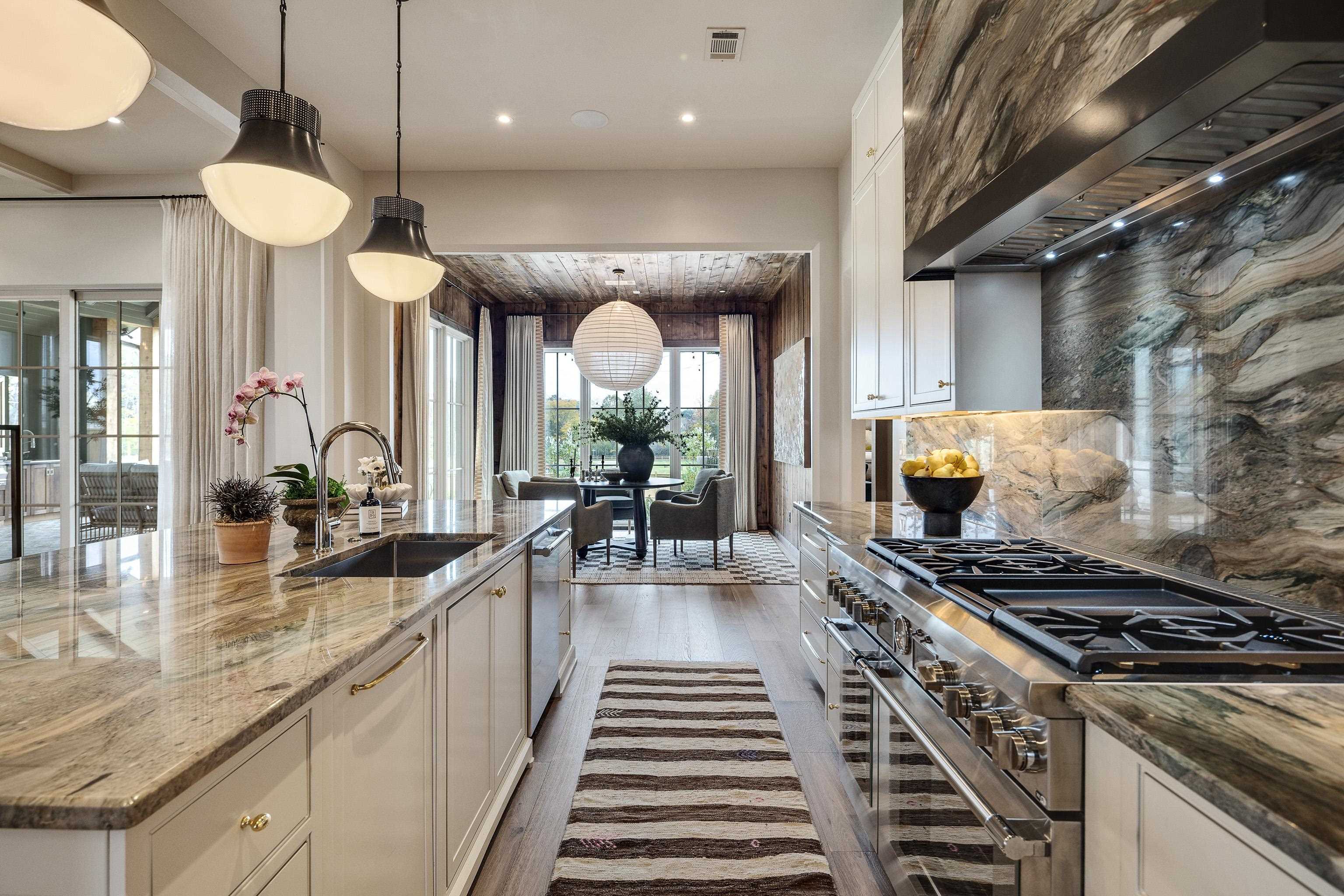 3310 Hidden Creek Loop Collierville, TN 38017 - Photo 10 of 40 Kitchen with white cabinetry, dark stone counters, exhaust hood, stainless steel appliances, and decorative light fixtures