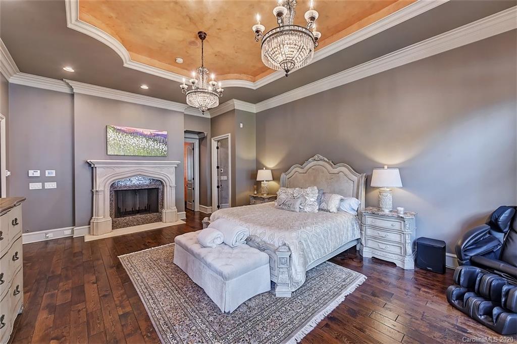 16505 Jetton Road Cornelius, NC 28031 - Photo 26 of 48 a spacious bedroom with a bed chandelier and a fireplace