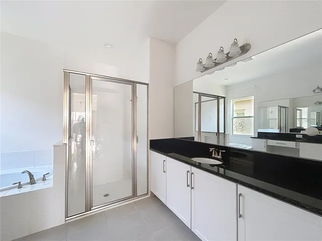 a spacious bathroom with a granite countertop sink a mirror and a bathtub