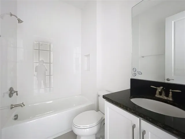 a bathroom with a granite countertop sink a toilet and bathtub