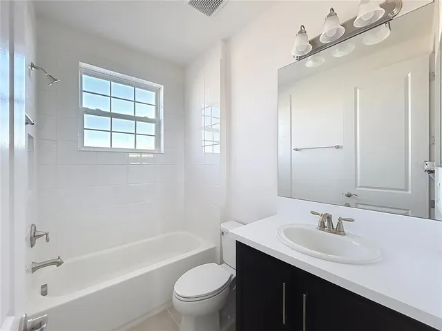 a bathroom with a bathtub shower sink mirror vanity and toilet