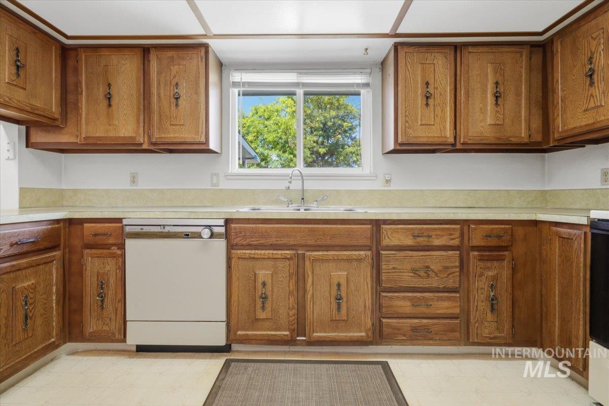 1311 North Middleton Road Nampa, ID 83651 - Photo 37 of 49 Kitchen featuring wood cabinetry with decorative hardware, a light-colored countertop, and a double basin sink