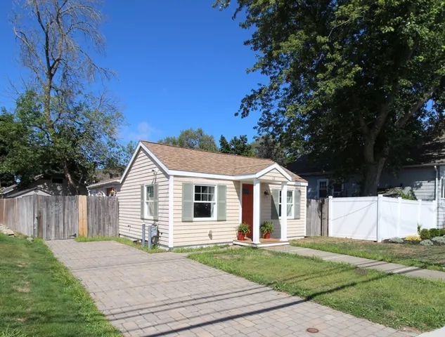 a view of a yard in front of a house with plants and large tree
