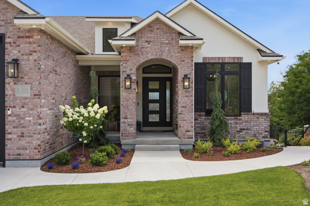 12308 Mariah Circle Draper, UT 84020 - Photo 168 of 293 Guest House Brick and stucco exterior featuring a contemporary front entry door with obscure glass panels, an arched brick portico, black decorative shutters, and mature landscaping