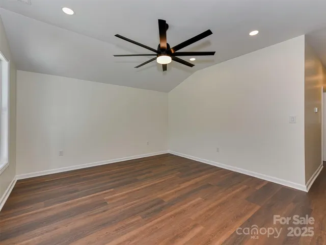 an empty room with wooden floor and a ceiling fan
