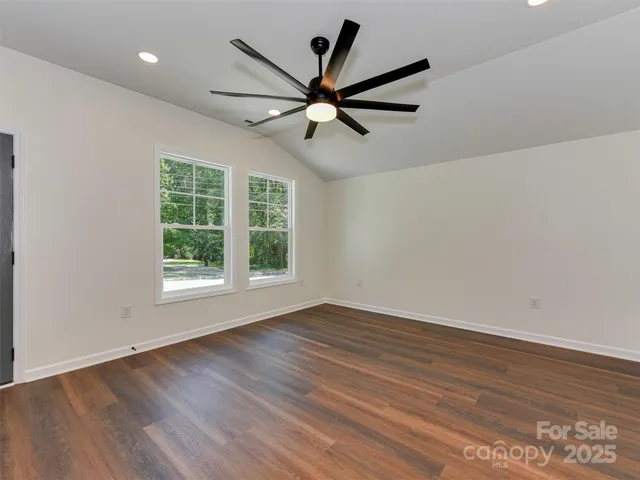 an empty room with wooden floor fan and windows
