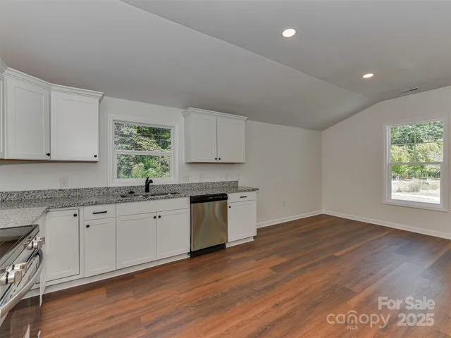 a kitchen with granite countertop white cabinets and sink