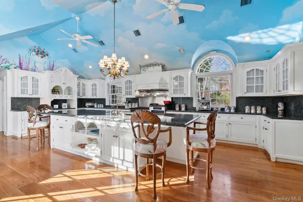 a kitchen with stainless steel appliances kitchen island granite countertop a stove top oven a sink a dining table and chairs with wooden floor