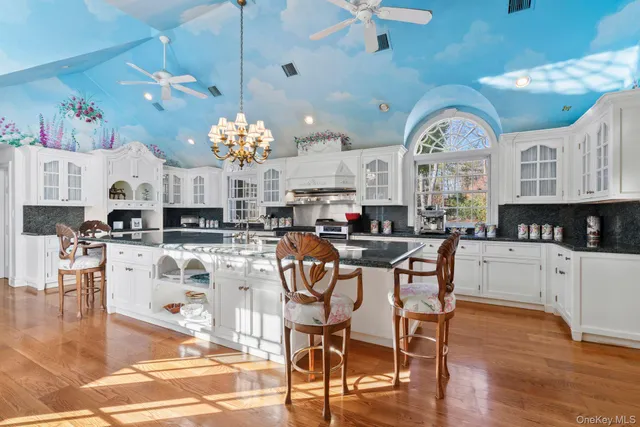 a kitchen with stainless steel appliances kitchen island granite countertop a stove top oven a sink a dining table and chairs with wooden floor