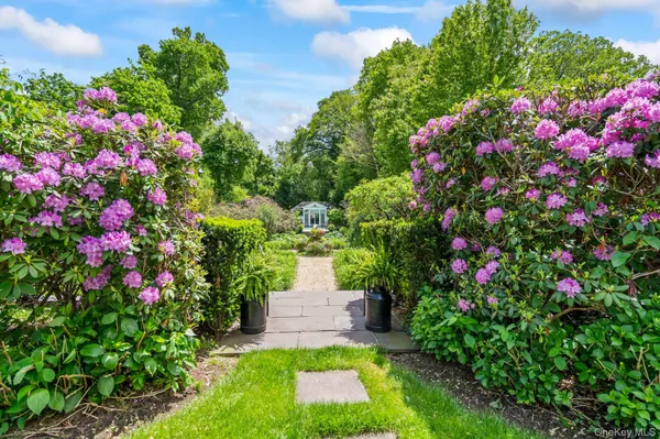 a view of a white house with a large space and a road
