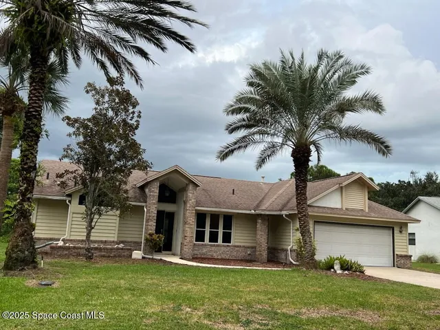 a front view of a house with a garden and palm tree