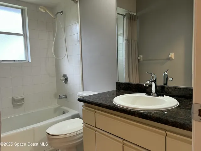 a bathroom with a granite countertop sink toilet mirror and bathtub