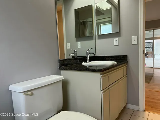 a bathroom with a granite countertop toilet sink and mirror