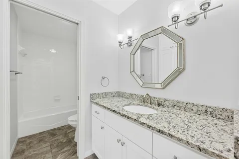 a bathroom with a granite countertop sink a mirror and a bathtub