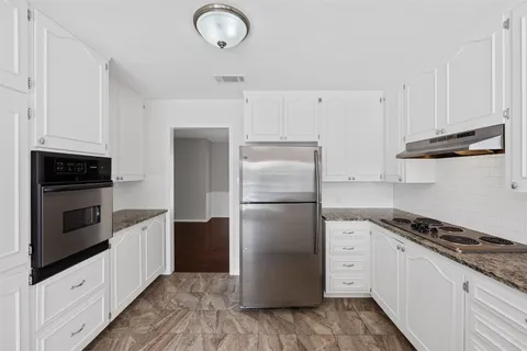 a kitchen with a refrigerator stove and white cabinets