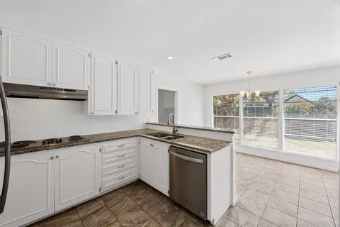 a kitchen with granite countertop a sink and white cabinets