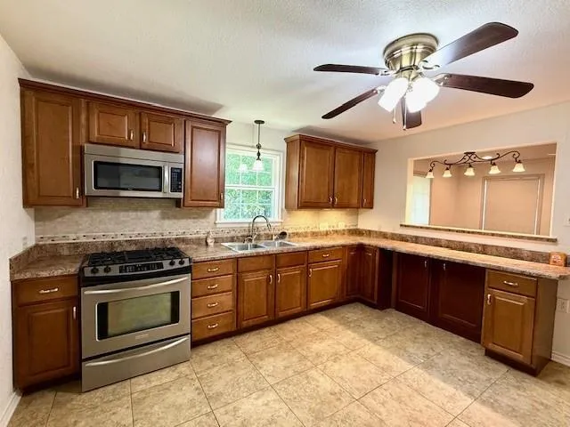 a kitchen with stainless steel appliances granite countertop a stove microwave and sink
