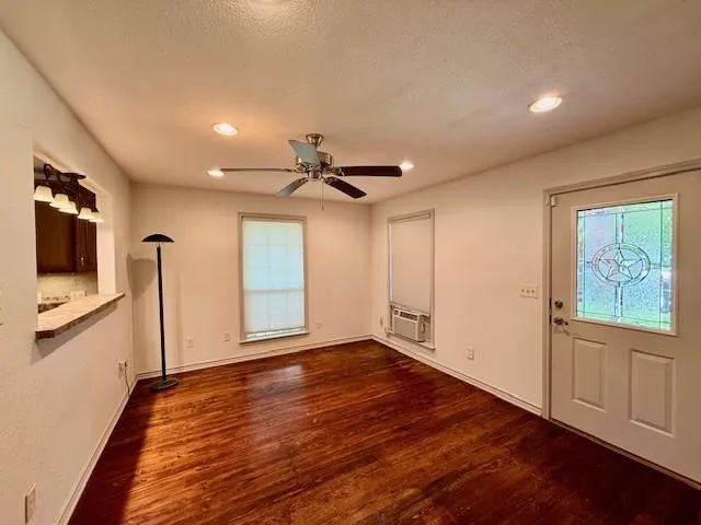a view of empty room with wooden floor and fan